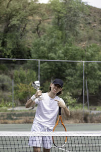 Vertical view of excited young teenager pointing his new champion winning cup holded on his hand