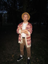 Portrait of young man standing against trees