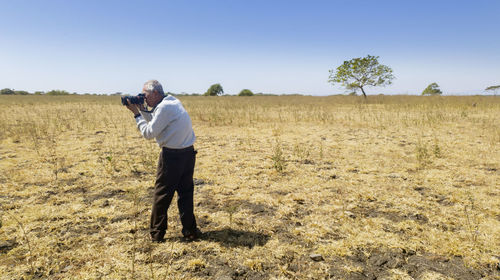 Full length of man photographing on field