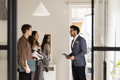 Salesman discussing with male and female clients while standing at home