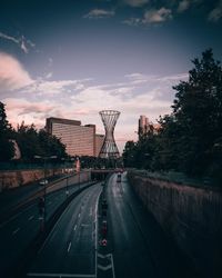 Road passing through city against sky