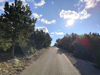 Empty road amidst trees against sky
