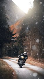 Man riding motorcycle on road in winter