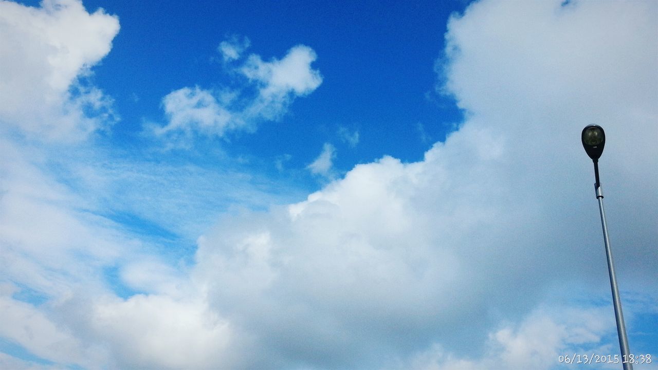 low angle view, sky, cloud - sky, street light, cloudy, blue, cloud, lighting equipment, pole, day, outdoors, nature, no people, weather, electricity, cable, white color, tranquility, beauty in nature, high section