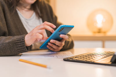 Midsection of woman using mobile phone on table