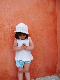 Full length of girl standing against red wall