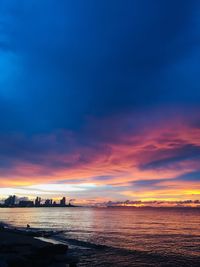 Scenic view of sea against dramatic sky during sunset