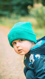 Little boy, dressed in warm clothes, walks in the autumn forest