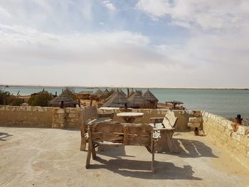 Chairs on table by sea against sky