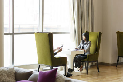 Business people working while sitting by window in office