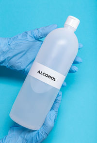 High angle view of hand holding bottle against blue background
