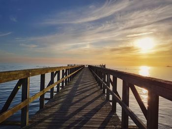 Pier over sea against sky during sunset