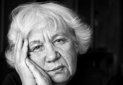 Portrait of sad senior woman against black background