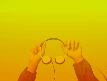 Close-up of hand holding yellow against orange background