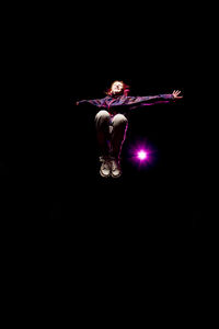 Low angle view of girl jumping against black background