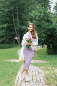 A young woman in white lilac clothes with an eco-bag with fruit on the background of nature