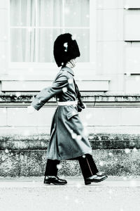 Side view of girl standing against building