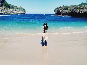 Woman standing on beach against sky