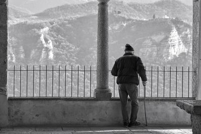 Rear view of man standing by railing against mountain