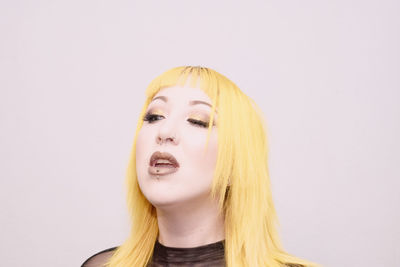 Close-up of young woman with blond hair against white background