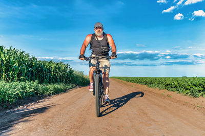 Man with a gray beard rides bicycle on field road. summer bike trip