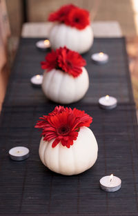 Close-up of red flowers in vases and tealight candles