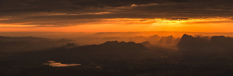 Scenic view of silhouette mountains against orange sky