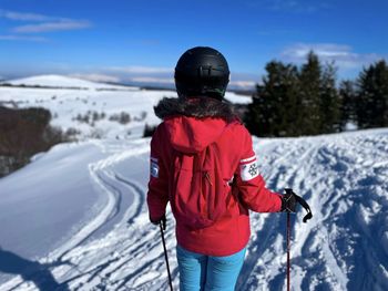 Woman skier on the slope looking at the snowcapped mountains on a sunny winter day