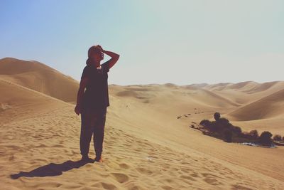 Woman standing on sand dune during sunny day