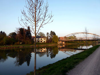 Reflection of houses and trees in water against clear sky