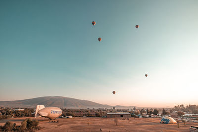 Hot air balloons flying over land against clear sky