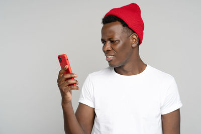 Midsection of man holding smart phone against white background