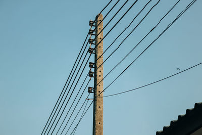 Low angle view of electricity pylon against clear blue sky