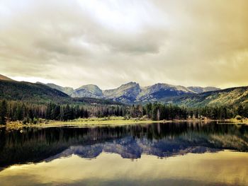 Scenic view of lake and mountains against cloudy sky