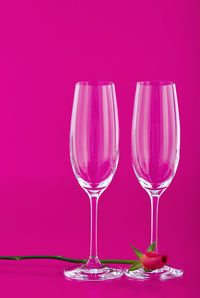 Close-up of wineglass on table against pink background
