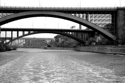Arch bridge over river in city against sky