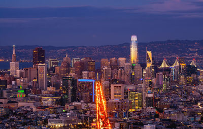 Aerial view of illuminated buildings in city against sky