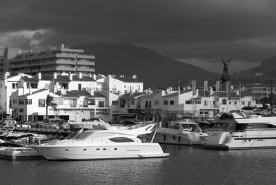 Sailboats moored at harbor against buildings in city