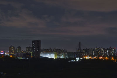 Illuminated cityscape against sky at night