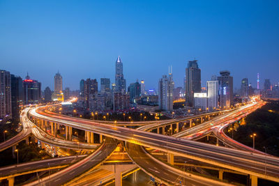 High angle view of light trails on road amidst buildings against sky