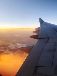 Close-up of airplane wing against sky during sunset