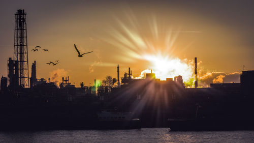 Silhouette city against sky at sunset