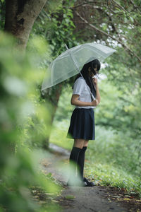 Woman standing on wet umbrella during rainy season