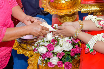 Midsection of woman holding seashell over bride hands during wedding ceremony