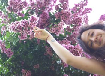 Low angle portrait of woman touching flowers in park