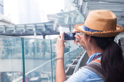 Midsection of woman holding hat in city