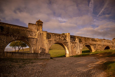 Arch bridge over river against sky