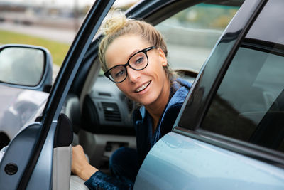 Portrait of young woman sitting in car