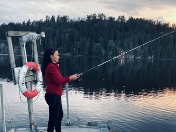 Full length of woman fishing on lake against sky