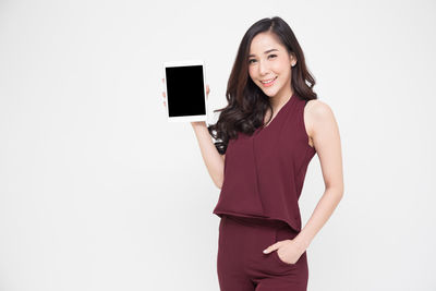 Portrait of a smiling young woman standing against white background